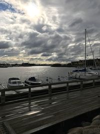 Boats moored in river against cloudy sky