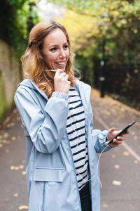 Young woman using mobile phone while standing on camera