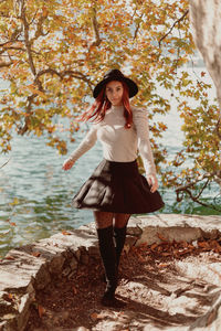 Portrait of young woman standing against tree