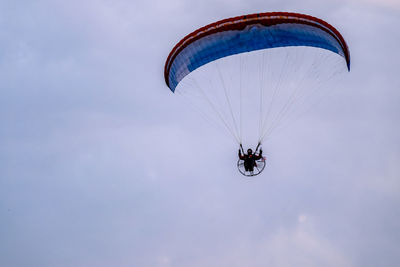 Low angle view of person paragliding against sky