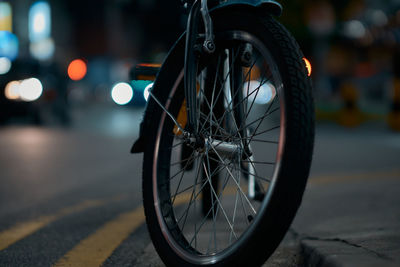 Close-up of bicycle parked on road at night