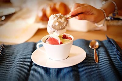 Close-up of hand holding ice cream on table