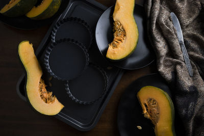 Pieces of sliced pumpkin on the dark table with dark dishes