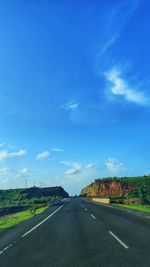 Road passing through landscape against blue sky