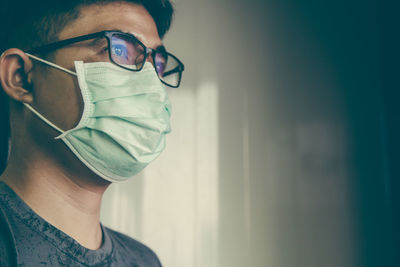 Young man wearing mask looking away at home