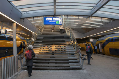 Rear view of man walking on escalator