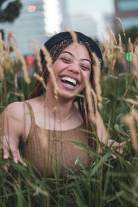 Portrait of happy young woman amidst plants on field