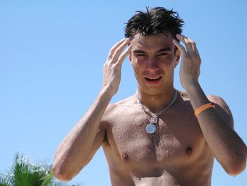 Low angle view of shirtless man against clear blue sky