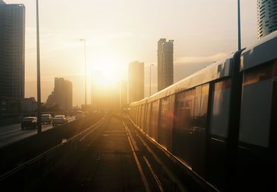 Train in city against sky during sunset