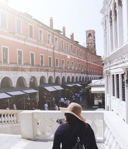 Rear view of woman wearing hat against buildings in city