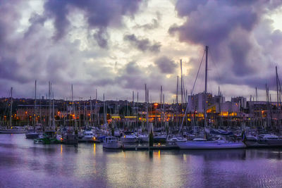 Sailboats moored on harbor against sky during sunset