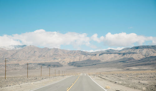 Road by mountains against sky