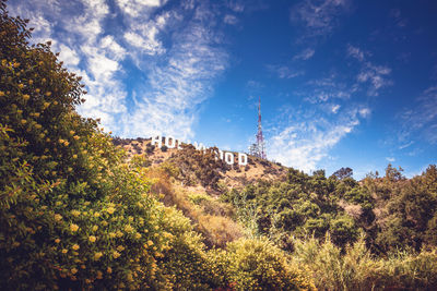 Low angle view of text on hill against sky