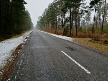 Empty road amidst trees against sky