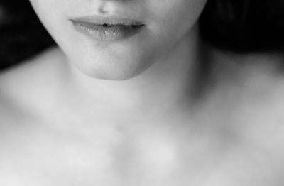 A black and white sensual close up of female lips, neck and shoulders