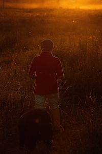 Rear view of silhouette man standing on field at night