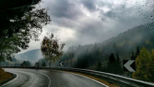 Road amidst trees against sky