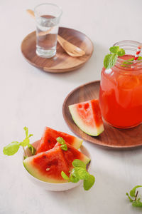 Watermelon drink in glass with slices of watermelon on whitebackground