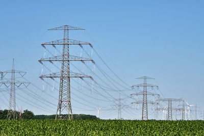 Electricity pylons and power lines with wind turbines in the back seen in germany