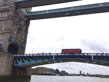 Low angle view of bridge over river against cloudy sky