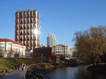 Buildings by canal against clear blue sky