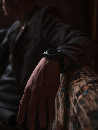 Midsection of man wearing watch sitting on sofa