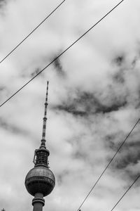 Low angle view of communications tower against cloudy sky