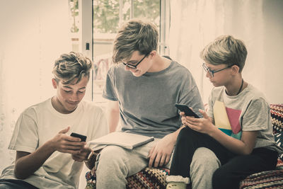 Siblings using phones while sitting at home