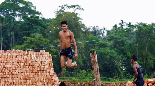 Full length of shirtless man against wall