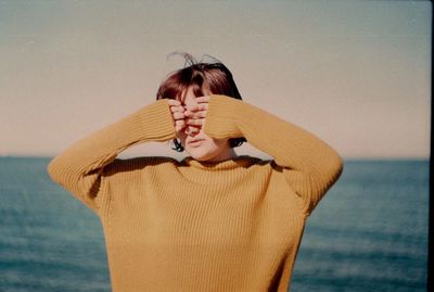 Young woman standing at beach against clear sky