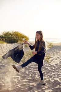 Portrait of a girl with long hair run on a sandy beach in a black leather jacket