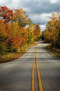 Road amidst autumn trees against sky