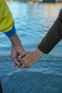 Midsection of man holding hands in swimming pool