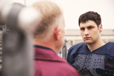 Coach discussing with american football player at stadium