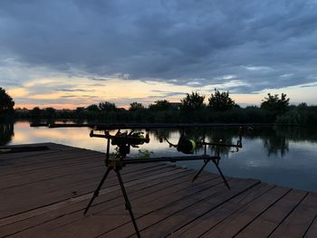 Pier on lake against sky during sunset