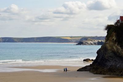 Rear view of man standing at beach against sky