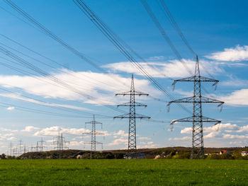 Low angle view of electricity pylon on field against sky