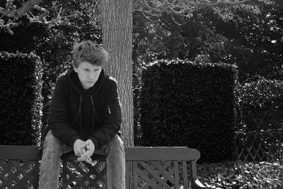 Boy sitting against trees