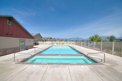 Swimming pool by building against blue sky