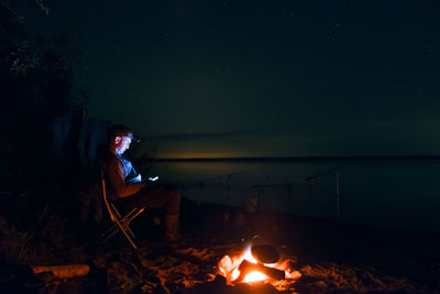 Silhouette on the shore of the lake near the fire. fisherman on the shore of the lake near the fire