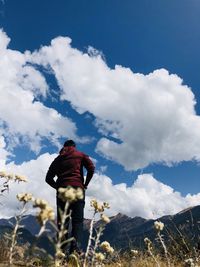 Rear view of man standing by mountain against sky