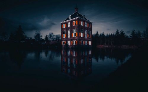 Reflection of building in lake against sky at dusk