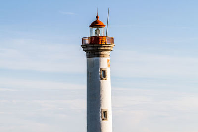 Low angle view of lighthouse by building against sky