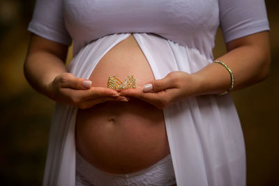 Midsection of pregnant woman holding crown