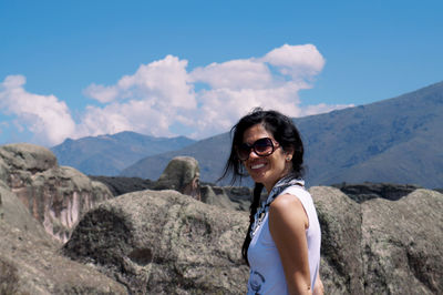 Portrait of smiling woman standing against mountain