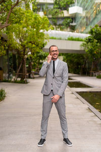 Portrait of young man standing against trees