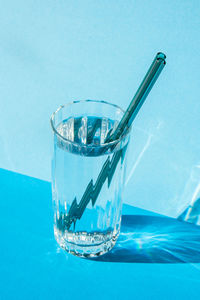 Reusable glass straws in glass with water on blue background eco-friendly drinking straw set with