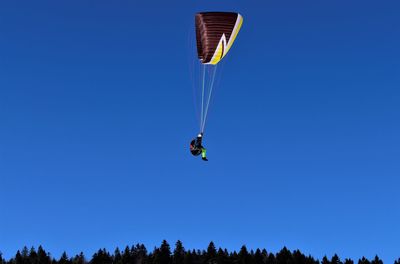 Low angle view of person paragliding against clear blue sky