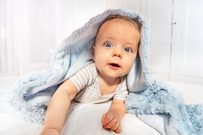 Portrait of cute baby girl lying on bed at home