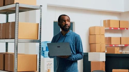 Side view of young man using digital tablet while standing in office